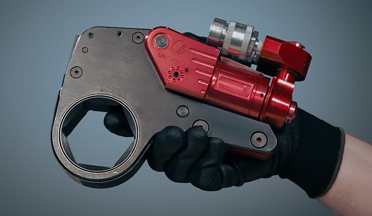 A gloved hand holds the XLCT Low Clearance Hydraulic Torque Wrench.